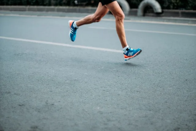 Jambes d'un coureur en foulée sur une route bitumée